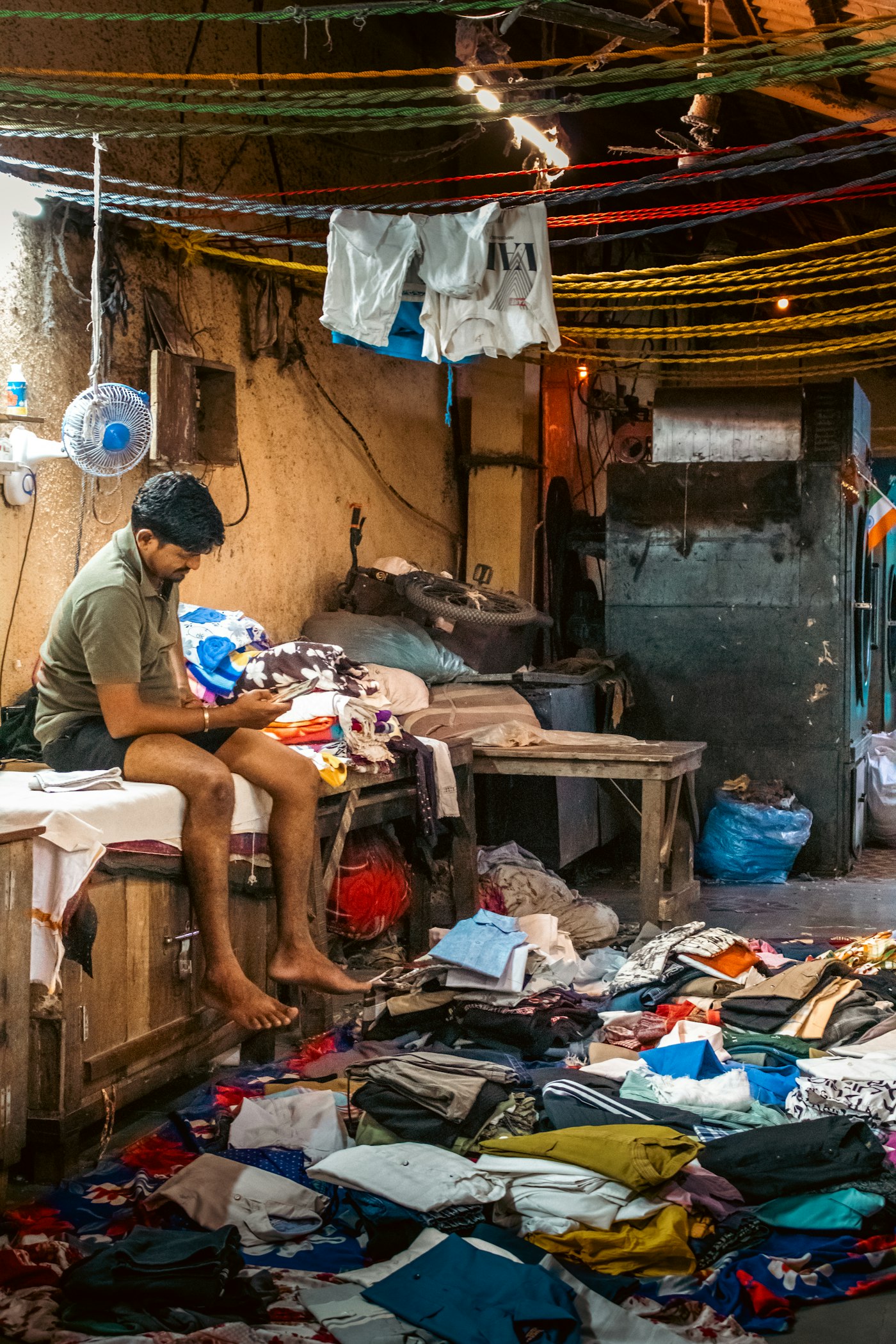 Person surrounded by clothing piles, sorting