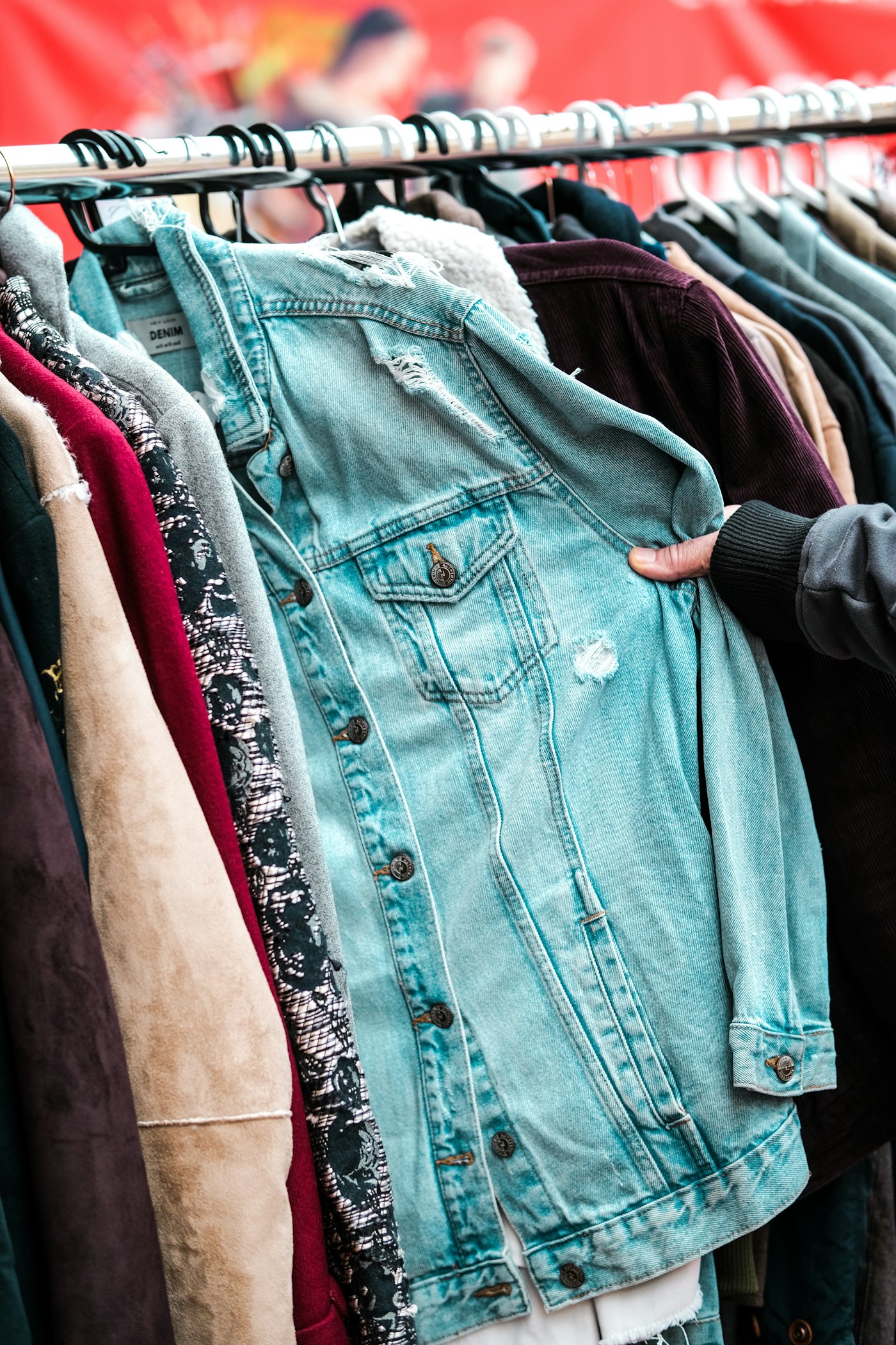 Person holding a jacket on a market rack